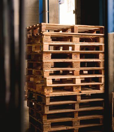 Stack of wooden shipping pallets beside a warehouse door