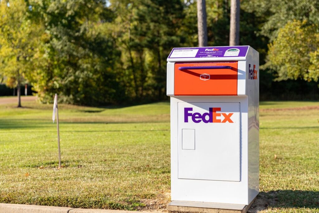 A FedEx drop box standing in a grassy roadside verge