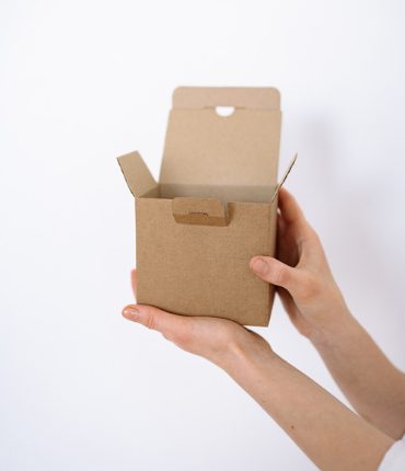 Two hands holding an open cardboard box