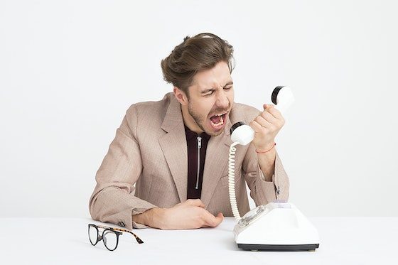 Frustrated man shouting into a telephone handset