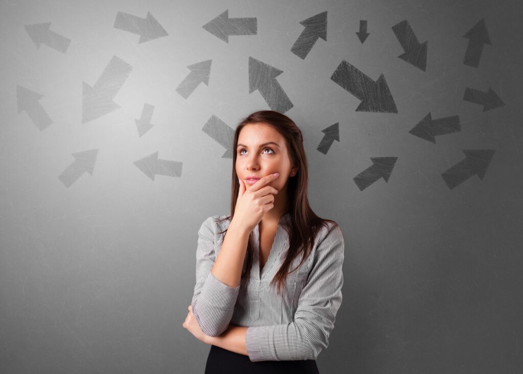 Woman considering a wall of arrows pointing in many directions