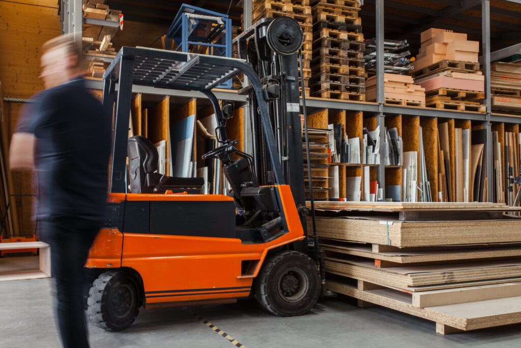 Forklift moving stacked pallets through a warehouse aisle